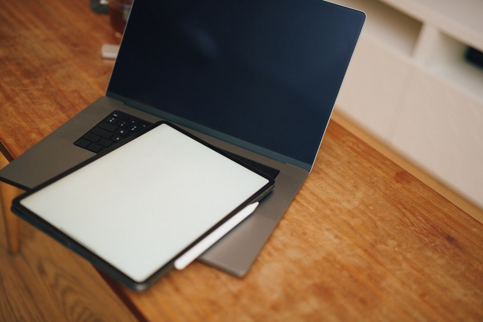 Open laptop with a graphic tablet on a wooden desk, perfect for design and digital workspaces.