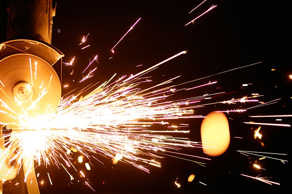 High-speed close-up of an angle grinder producing bright sparks against a dark background, capturing motion and intensity.