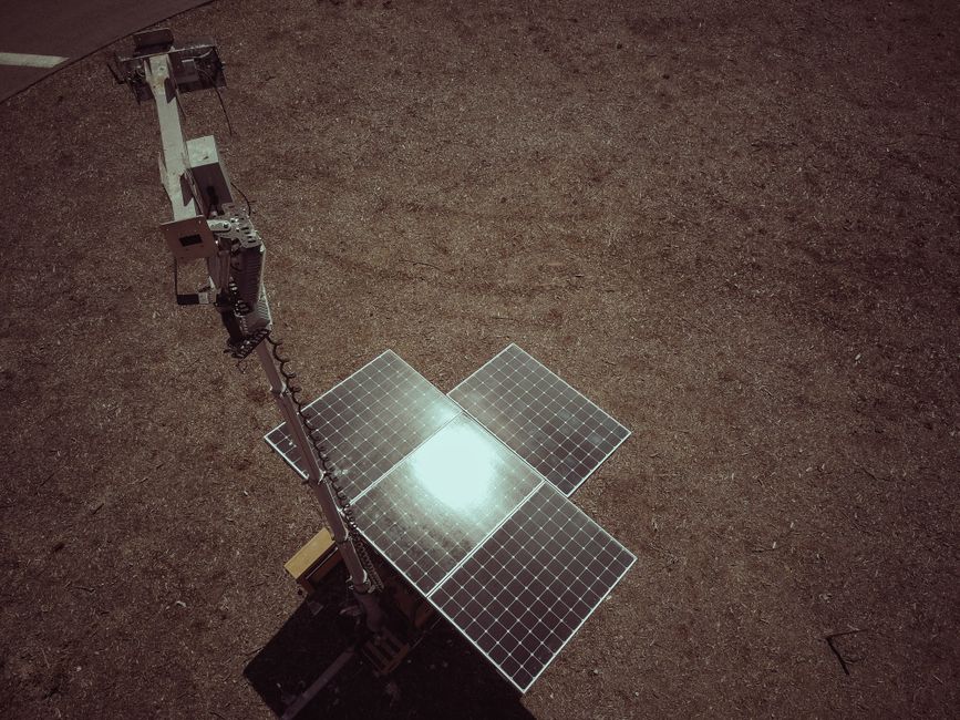Aerial shot of a solar panel on a deserted landscape, reflecting sunlight.