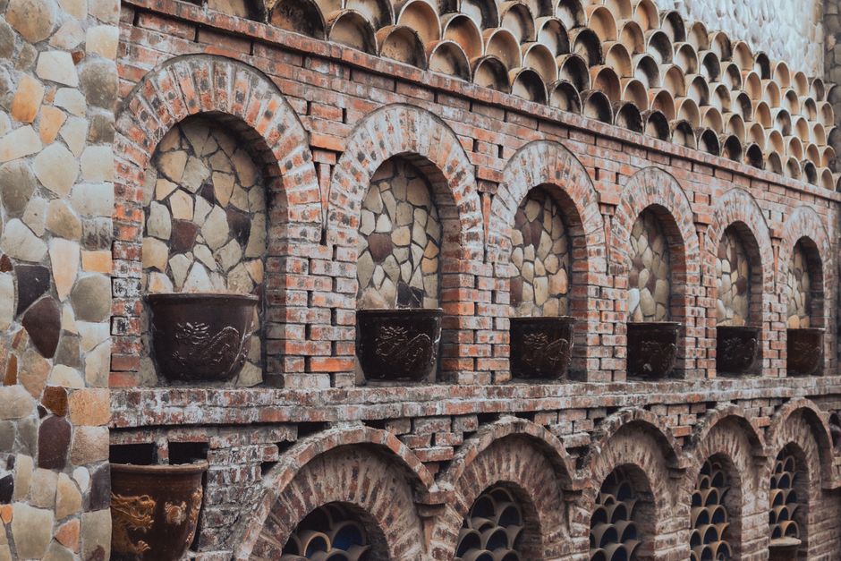 A detailed view of a rustic brick wall featuring arched niches and stone textures.
