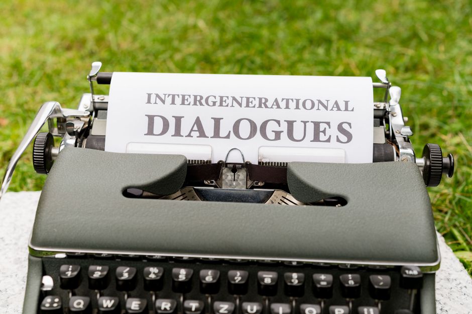 Close-up of a vintage typewriter outdoors with paper reading 'Intergenerational Dialogues'.
