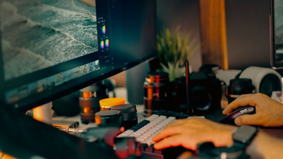 A digital editing workspace showcasing a computer screen with photo editing software open, surrounded by camera equipment.