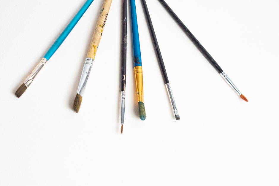 A collection of diverse paint brushes arranged on a plain white surface.