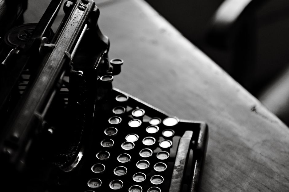 Black and white image of a classic typewriter on a wooden desk, evoking nostalgia.