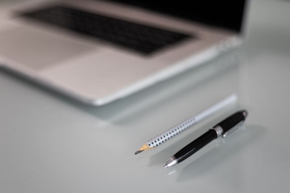 A close-up of a laptop on a desk with a pencil and pen, representing a modern workspace.