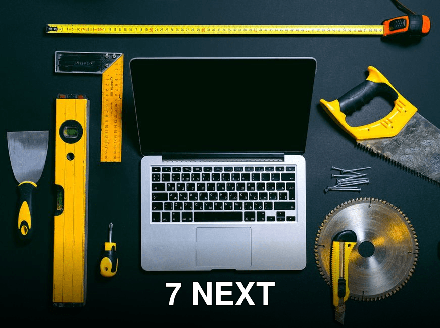 Overhead view of a laptop surrounded by various hand tools on a dark background, representing technology and construction.