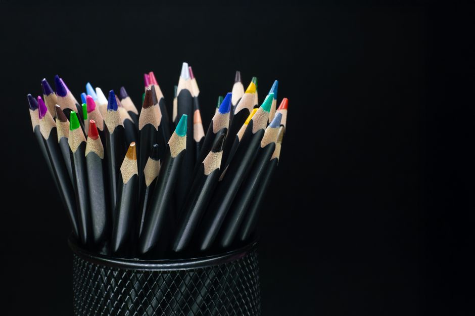 A collection of colorful pencils arranged in a black holder against a contrasting dark background.