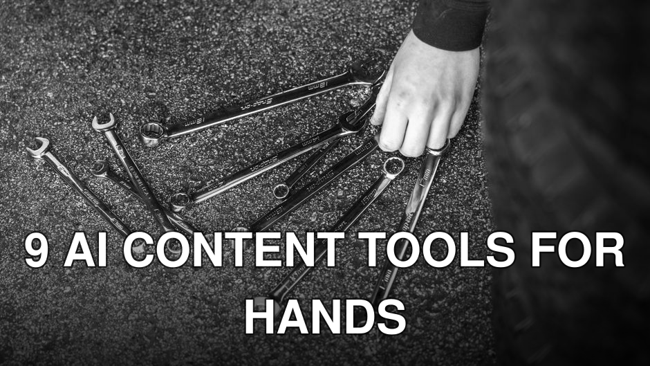 Black and white image of wrenches spread on asphalt with a hand picking up one.