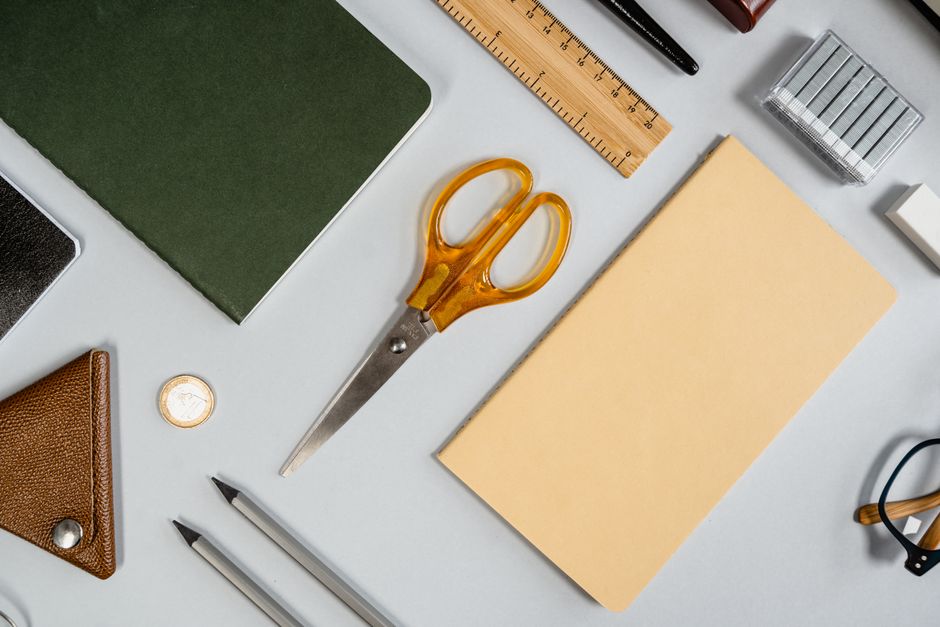 Flat lay showcasing various office supplies including scissors, notebook, ruler, and pencil.