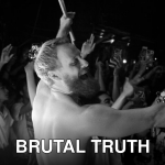 Black-and-white photo of a lively shirtless performer on stage with an enthusiastic crowd.