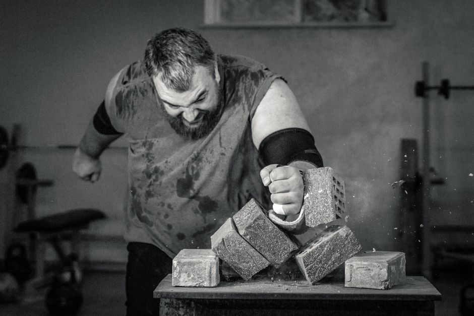 A powerful image of a strongman smashing concrete blocks with his fist, showcasing strength and determination.