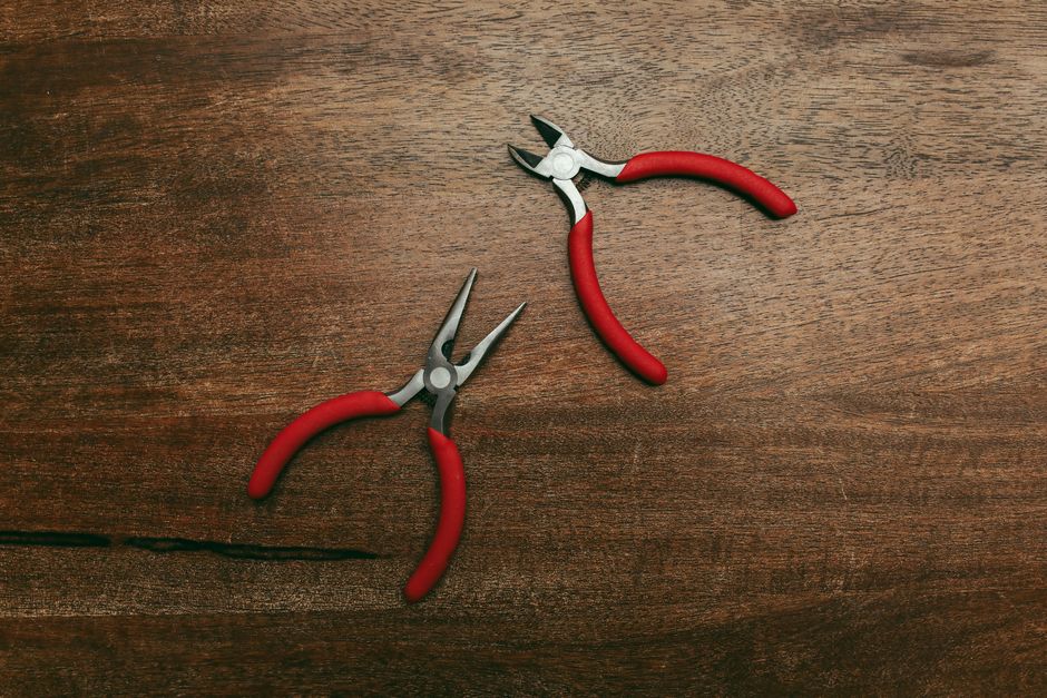 Close-up of two red-handled pliers on a wooden surface, perfect for tool-related themes.