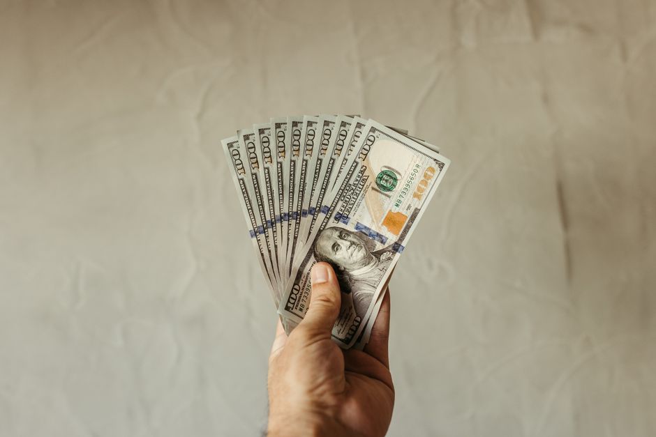 A close-up of a hand holding multiple US dollar bills, showcasing wealth and finance concepts.