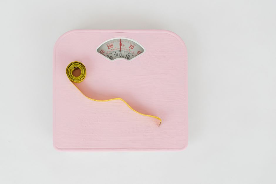 Top view of floor scales for weight control and measuring tape for controlling body shapes on white background