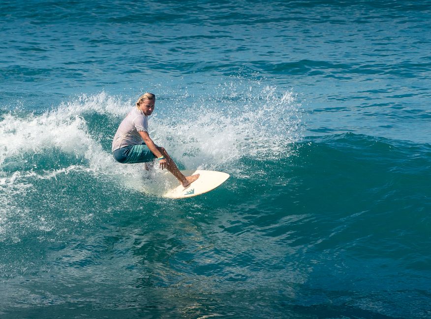 Blonde surfer expertly riding a wave, showcasing summer fun and adventure at sea.
