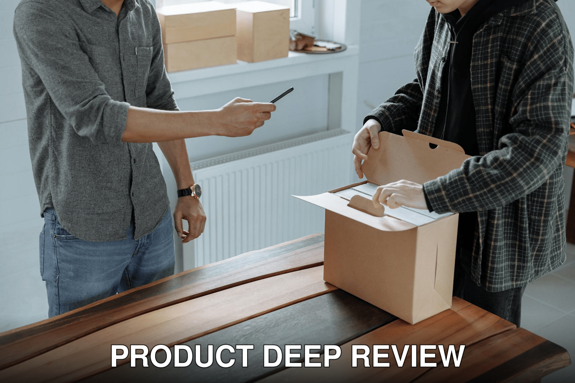 Two adults unpack and photograph a cardboard box using a smartphone indoors.