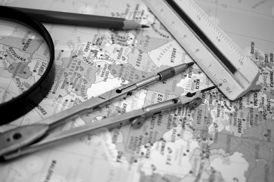 Black and white close-up of a compass and ruler on a map for cartographic purposes.