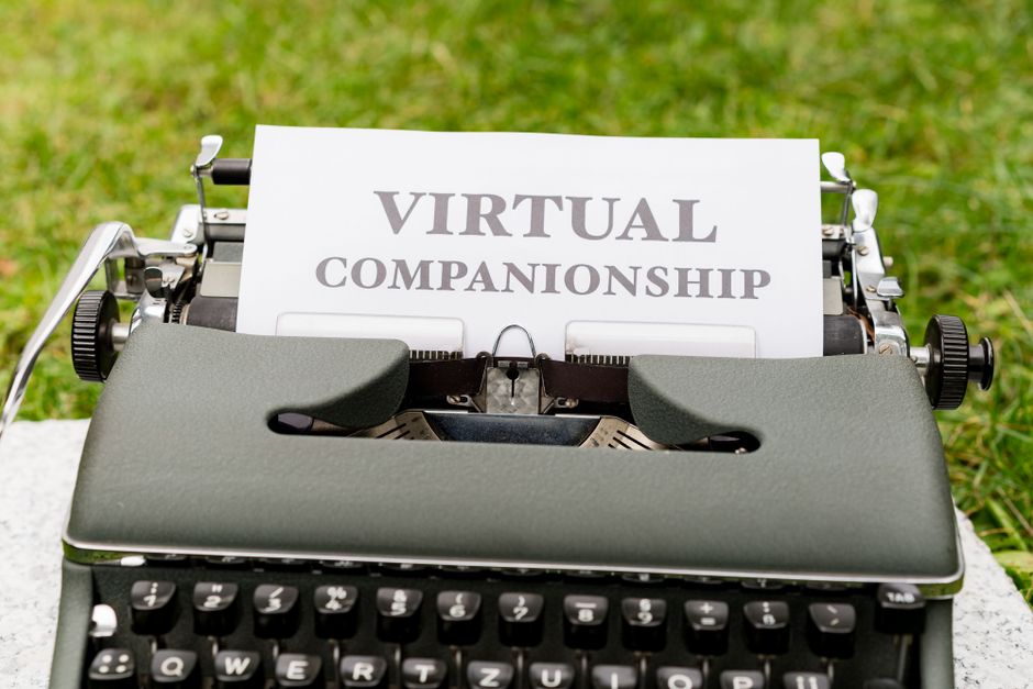 Typewriter on grass with paper showing text 'Virtual Companionship'.