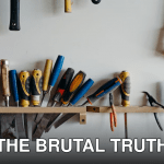 A neatly arranged collection of hand tools including chisels, saws, and screwdrivers in a workshop.