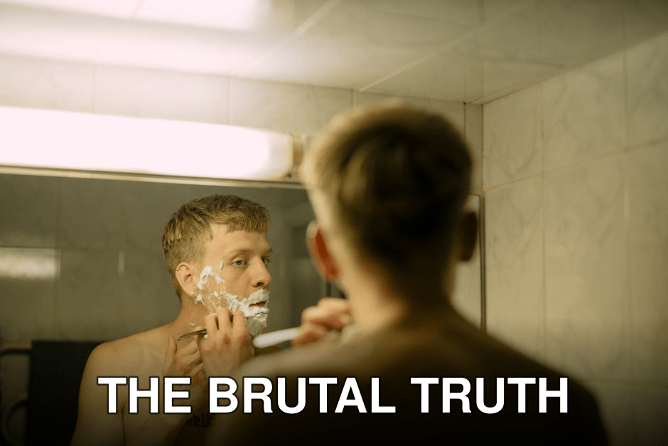 Adult man shaving in a bathroom mirror, highlighting daily grooming routine.