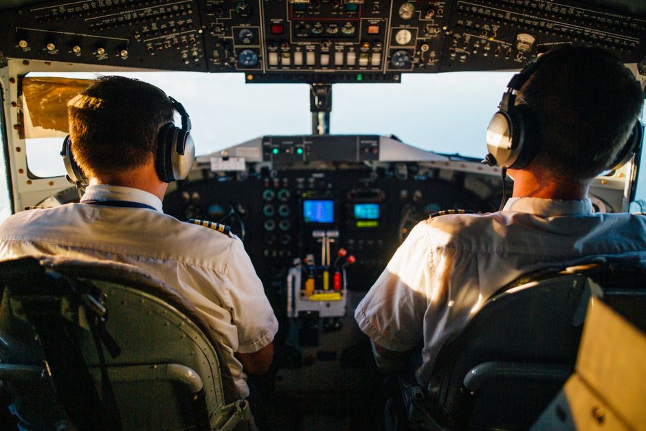Two pilots in cockpit navigating airplane at high altitude, daylight