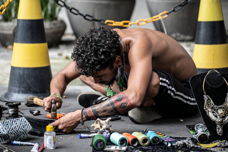 A tattooed artisan crafting jewelry in São Paulo, Brazil, showcasing art and skills.