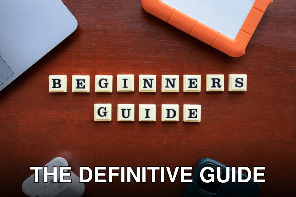 Creative flat lay of gadgets and 'Beginners Guide' text on wooden table.