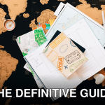 A flat lay of travel planning items on a map, featuring a compass, notebook, and guide for wanderlust enthusiasts.