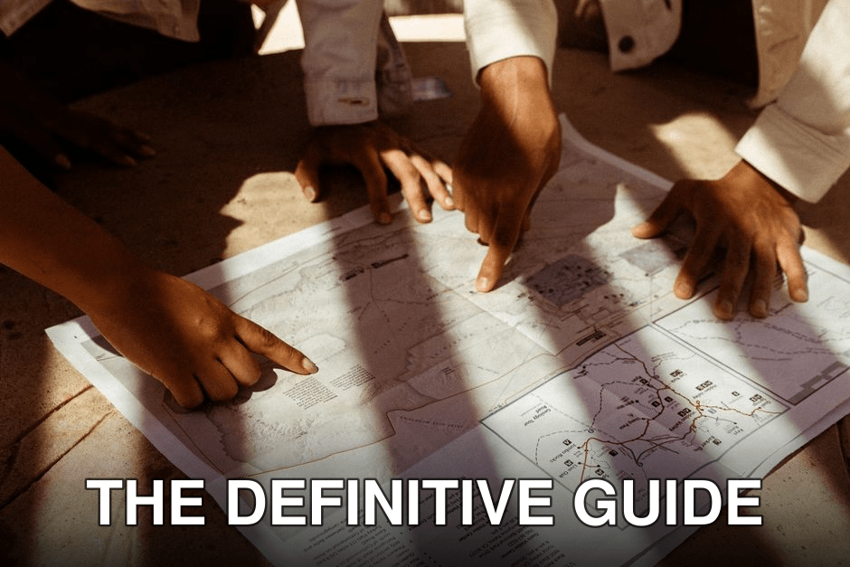 Group of hands pointing at a detailed map, planning an adventure trip in sunlight.