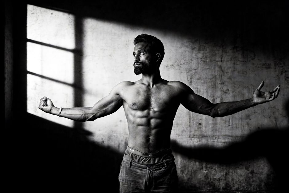 Artistic black and white portrait showcasing a muscular man with dramatic lighting.