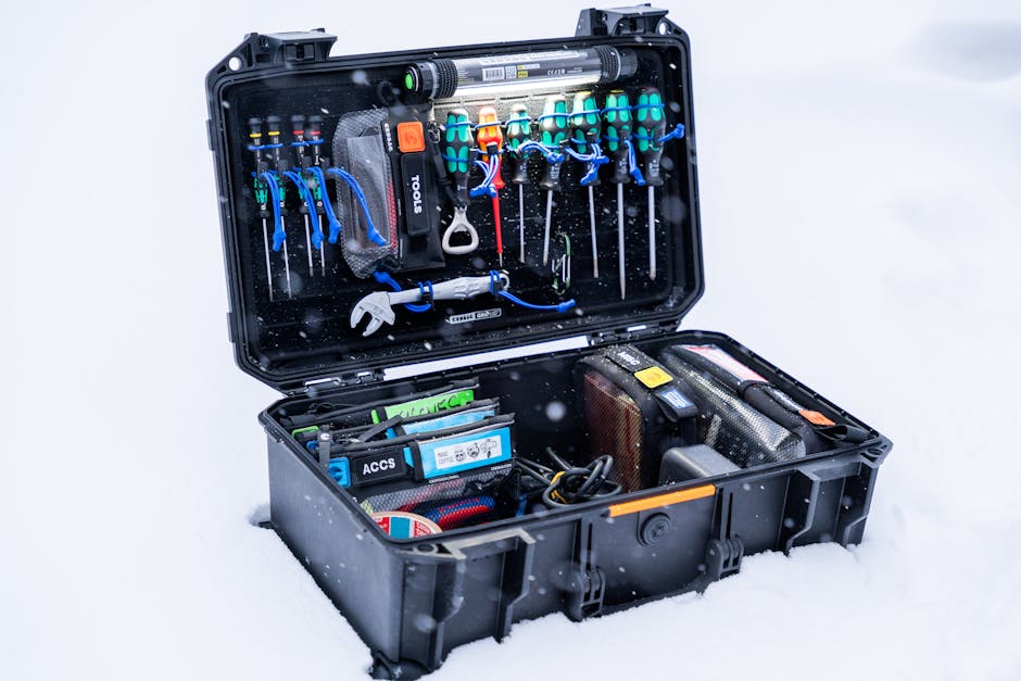 An open professional tool case filled with various tools and equipment, set in a snowy outdoor environment.