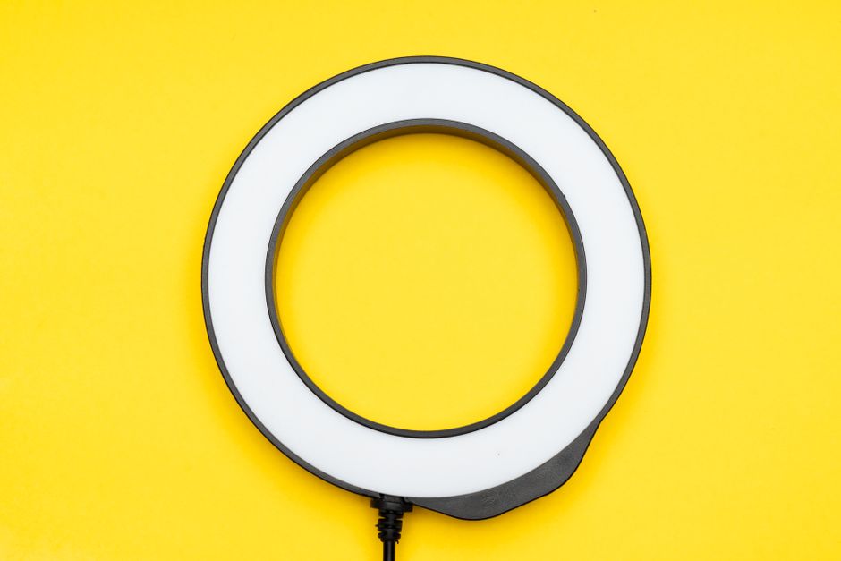 Close-up of a circular LED ring light against a vibrant yellow background.