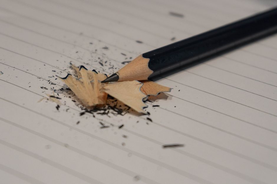 Detailed shot of a freshly sharpened pencil with shavings on lined paper, ideal for education themes.