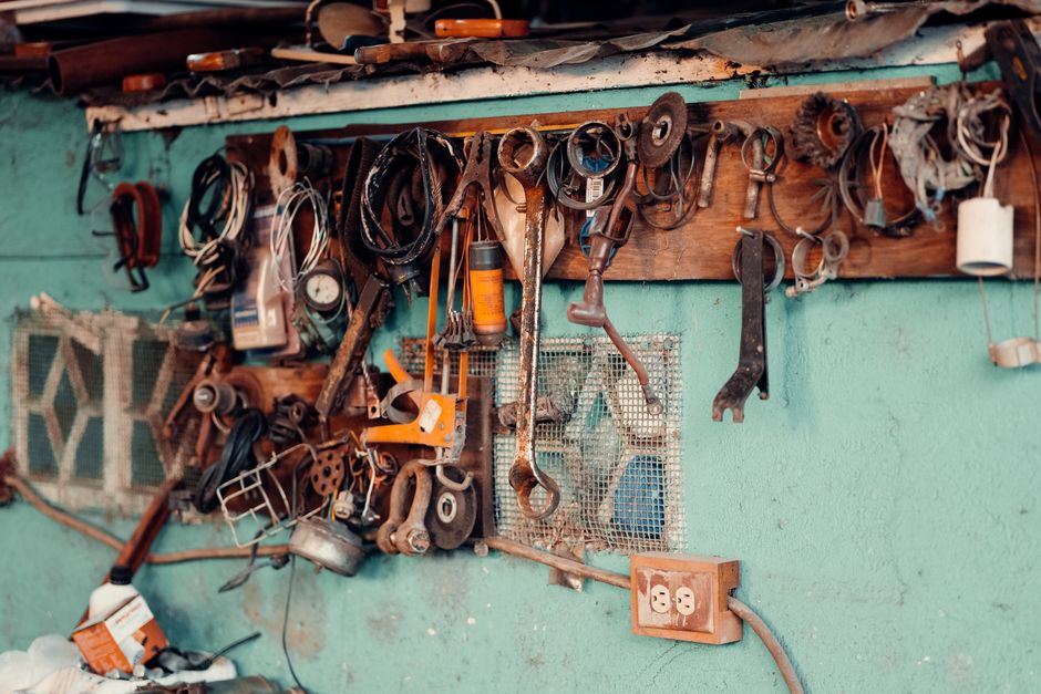 A collection of vintage tools hangs on a rustic workshop wall, creating a nostalgic and creative atmosphere.