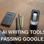 From above of small calculator pens and tape dispenser on wooden desk in office
