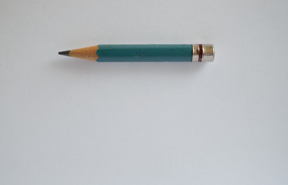 Minimalist image of a sharpened green pencil on a plain white background.