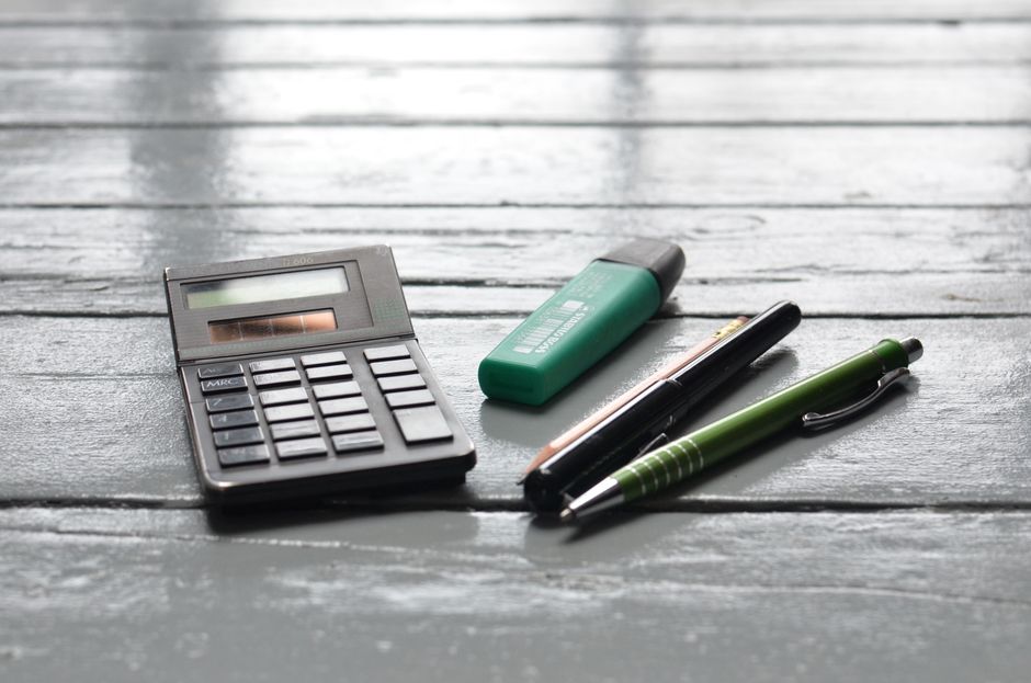 High angle of small electronic calculator green marker and pens on wooden table in office