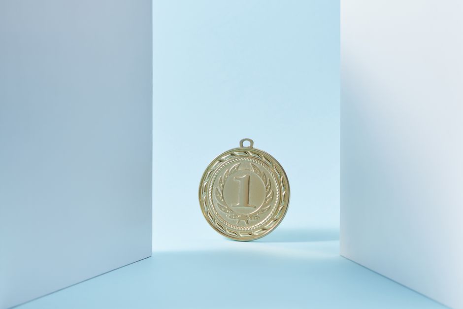 A gold medal displaying the number one, set against a light blue background.