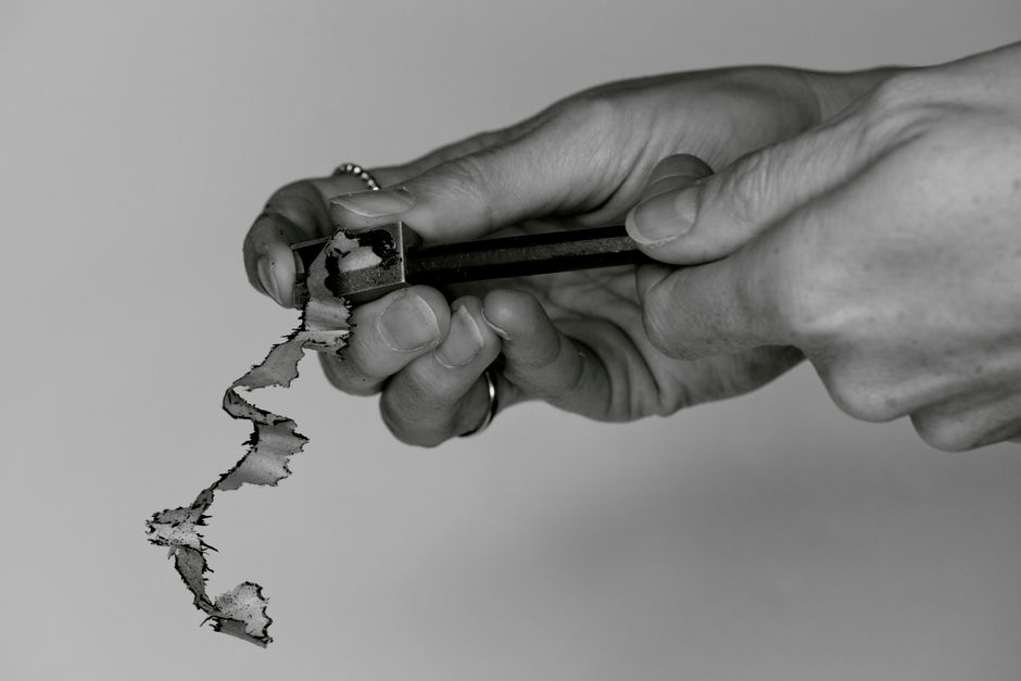 Monochrome image of hands sharpening a pencil, focusing on precision and detail.