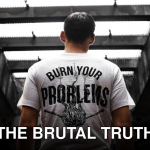 Man standing indoors, wearing a t-shirt with 'Burn Your Problems' text, viewed from behind.