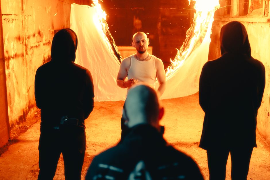Mysterious figures in an alley with a dramatic fire backdrop at night.