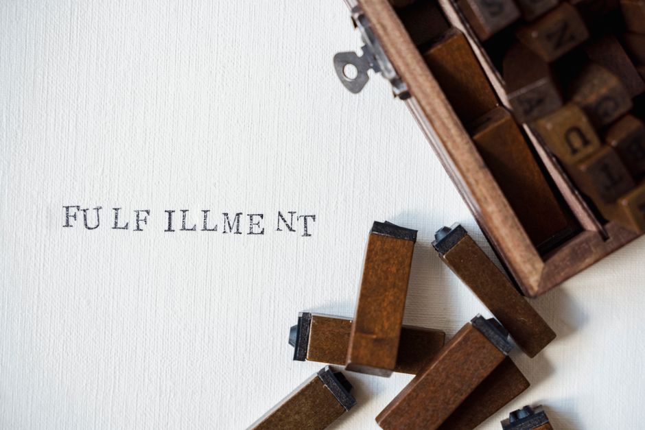 Closeup of wooden letter blocks and vintage typography, spelling 'FULFILLMENT' on canvas.