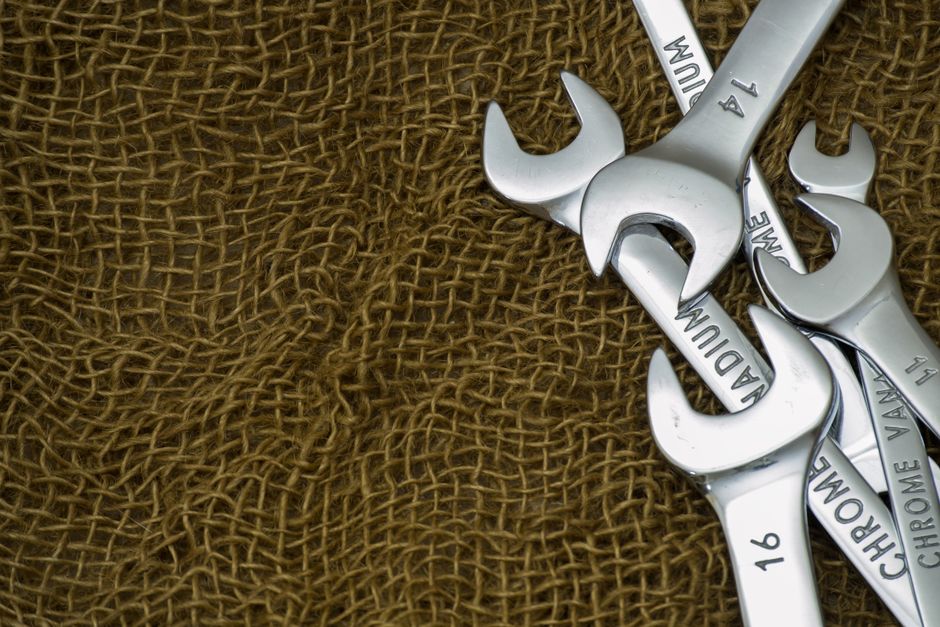 A collection of silver wrenches arranged on textured burlap fabric with visible engravings.